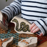 Child playing with the snake piece from the Bajo Gruffalo Character Puzzle in the Babipur playroom.
