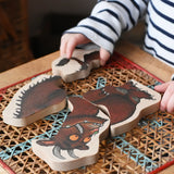 Child playing with Bajo Gruffalo character puzzle on a rattan stool in the Babipur playroom.