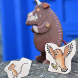 Mouse and owl pieces from the Bajo Gruffalo Character Puzzle placed on a stone wall in front of the Gruffalo figure.