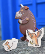 Mouse and owl pieces from the Bajo Gruffalo Character Puzzle placed on a stone wall in front of the Gruffalo figure.