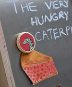 A close up of a Bajo gruffalo snake magnet stuck onto a Triclimb biri board. These magnets are part of a range of Bajo wooden toys available at Babipur. 