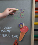 A child's hand drawing on a Triclimb biri board. A hand drawnice cream placed on the Triclimb Biri board with an owl Bajo magnet. These magnets are part of a range of Bajo wooden toys available at Babipur. 