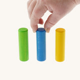 An adult's hand reaching for one of the wooden cylinder shaped pieces from the Bajo Hammering Board wooden toy. These heirloom quality toys by Bajo are part of a wide range of wooden toys available here at Babipur.