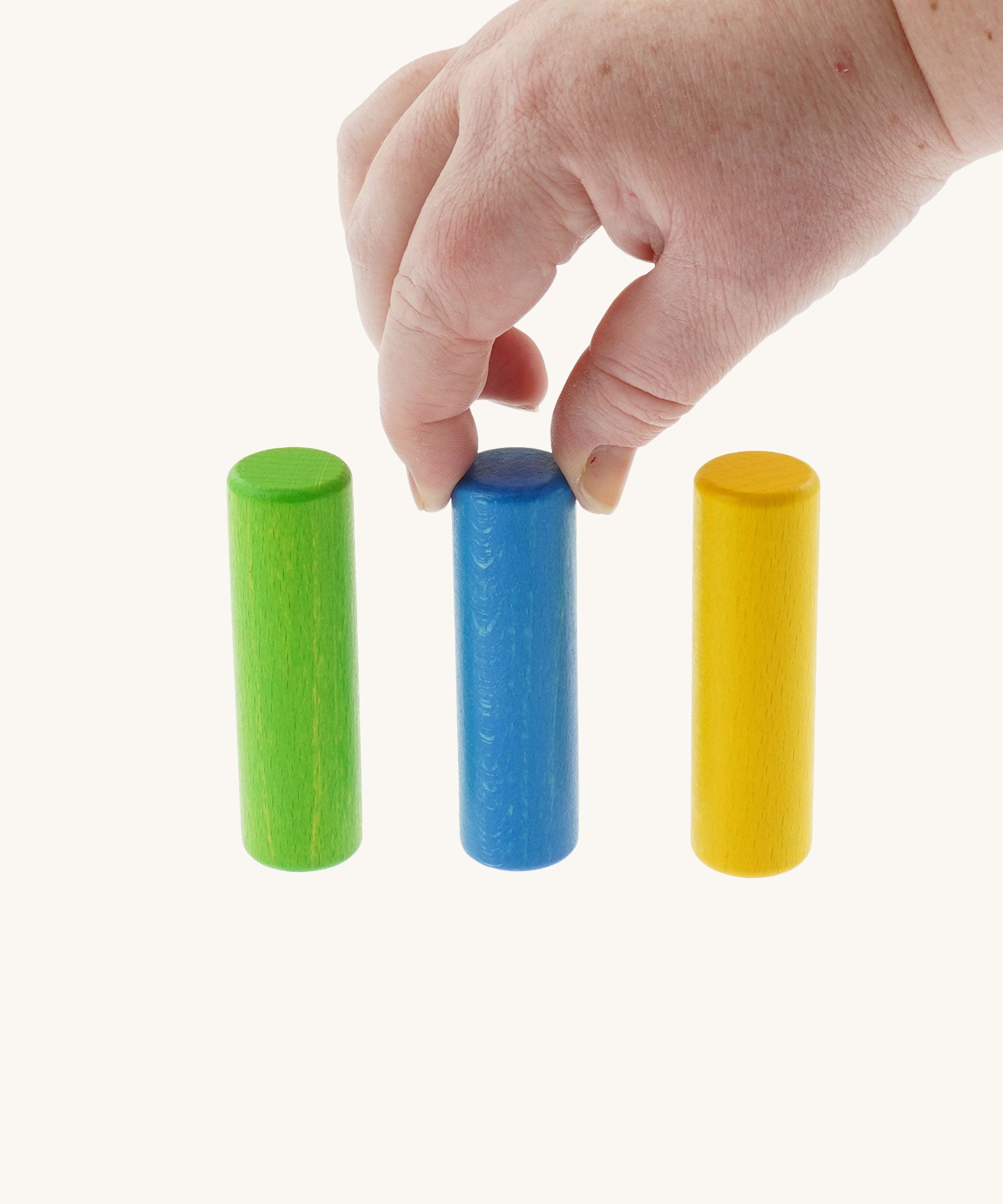 An adult's hand reaching for one of the wooden cylinder shaped pieces from the Bajo Hammering Board wooden toy. These heirloom quality toys by Bajo are part of a wide range of wooden toys available here at Babipur.
