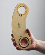 A close up of an adult's hand holding up a piece of the base from the Bajo Fellow Hoopla Game Set. A traditional style wooden game set that can be used for hoopla and skittles. These heirloom quality toys by Bajo are part of a wide range of wooden toys available here at Babipur.