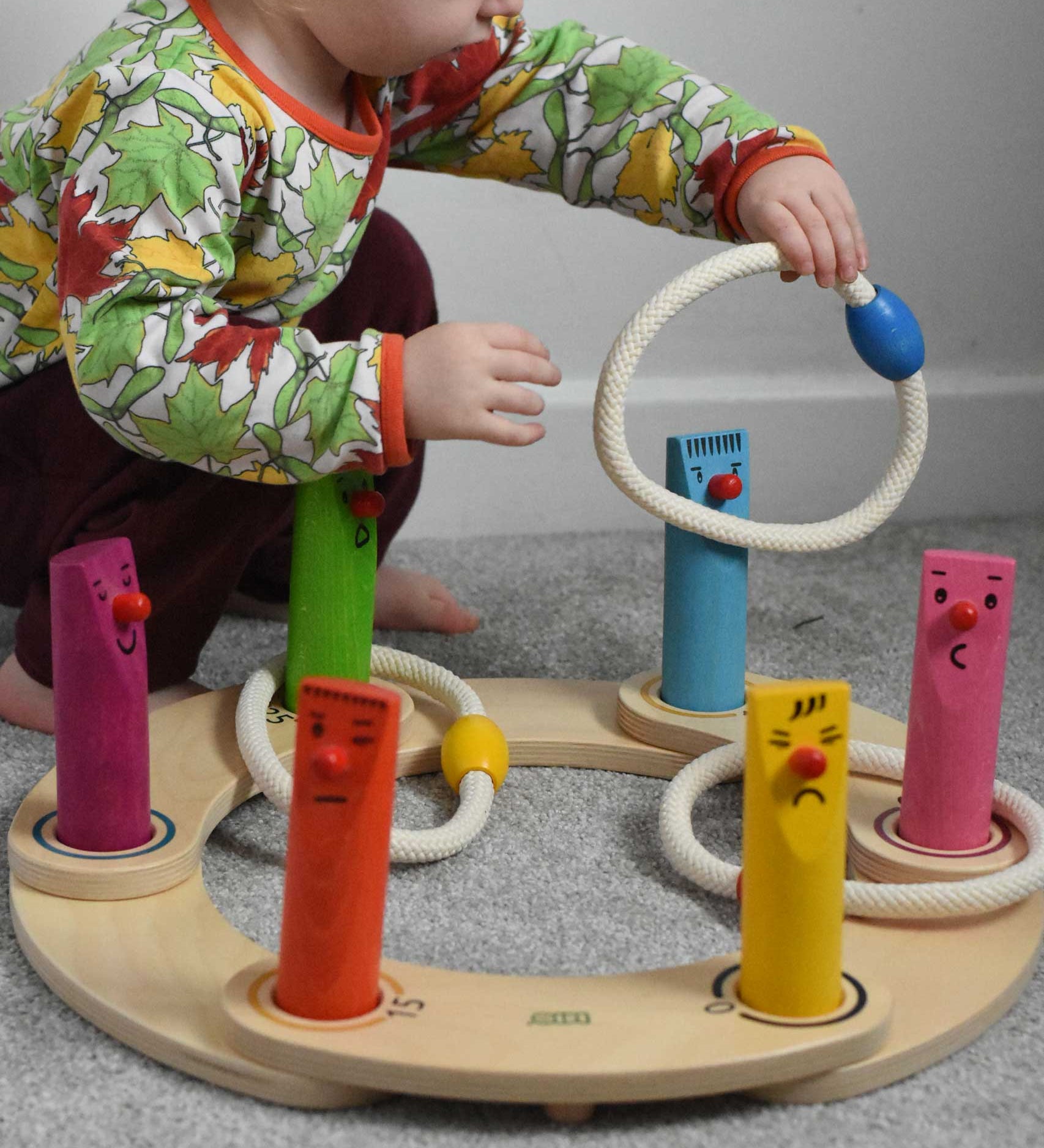 A young child playing with the Bajo Fellow Hoopla Game Set, set up as hoopla. A traditional style wooden game set that can be used for hoopla and skittles. These heirloom quality toys by Bajo are part of a wide range of wooden toys available here at Babipur.