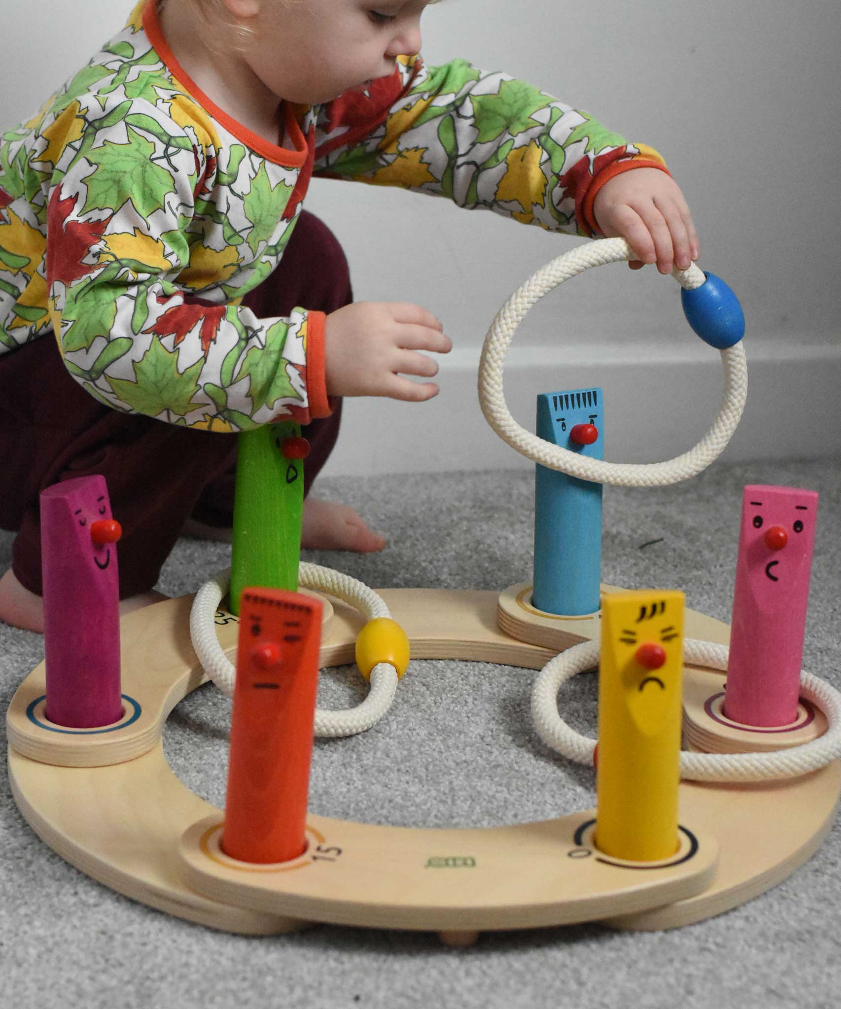 A young child playing with the Bajo Fellow Hoopla Game Set, set up as hoopla. A traditional style wooden game set that can be used for hoopla and skittles. These heirloom quality toys by Bajo are part of a wide range of wooden toys available here at Babipur.