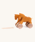 Bajo hand made wooden jumping horse in natural and available at Babipur. Features unpainted wheels  and a toggle to pull along the horses