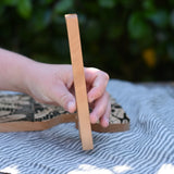 Child's hand holding for the giraffe shaped piece from the Bajo jungle puzzle showing the side.