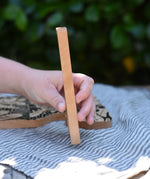 Child's hand holding for the giraffe shaped piece from the Bajo jungle puzzle showing the side.