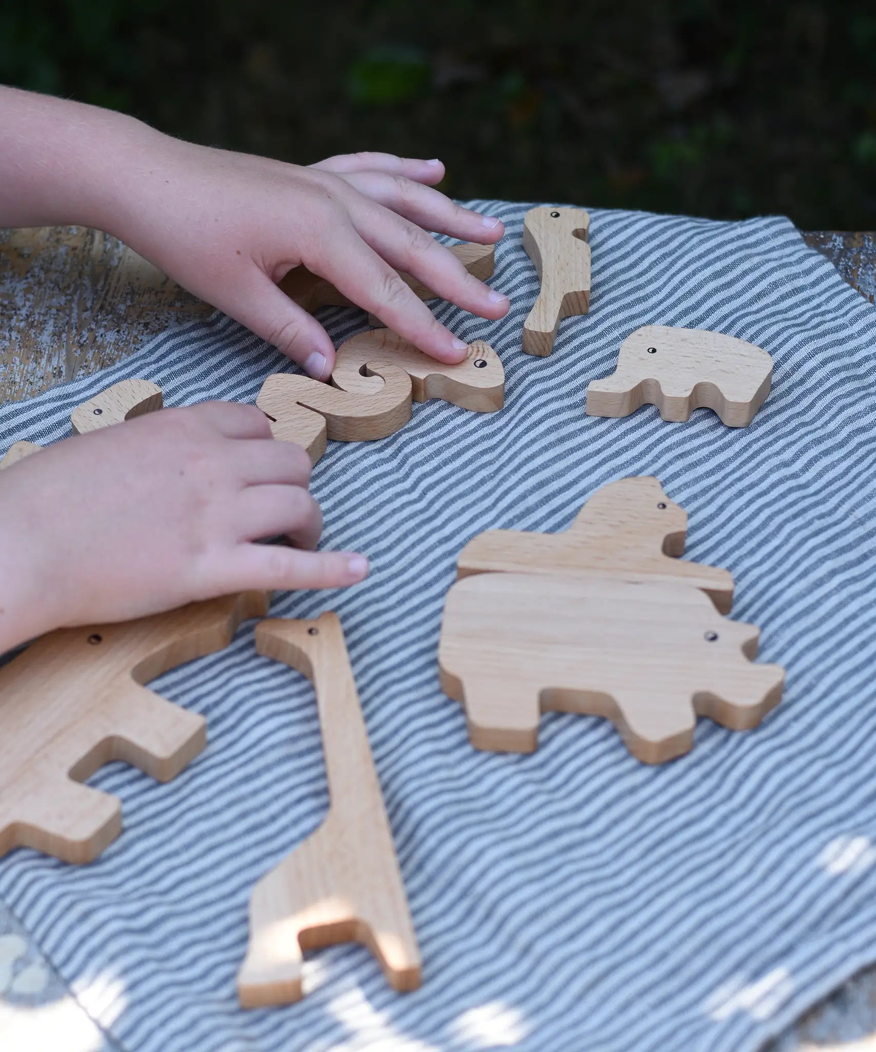 Child's hand slotting the animal shaped pieces from the Bajo jungle puzzle back together.