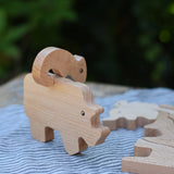 Bajo jungle puzzle , wooden animal shaped pieces one side plain natural wood, one side with a black pattern. Chameleon shaped pieced placed balancing on top of the rhino piece.