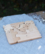 Bajo jungle puzzle shown on the natural wood side. Puzzle is made up of different animal shaped pieces.