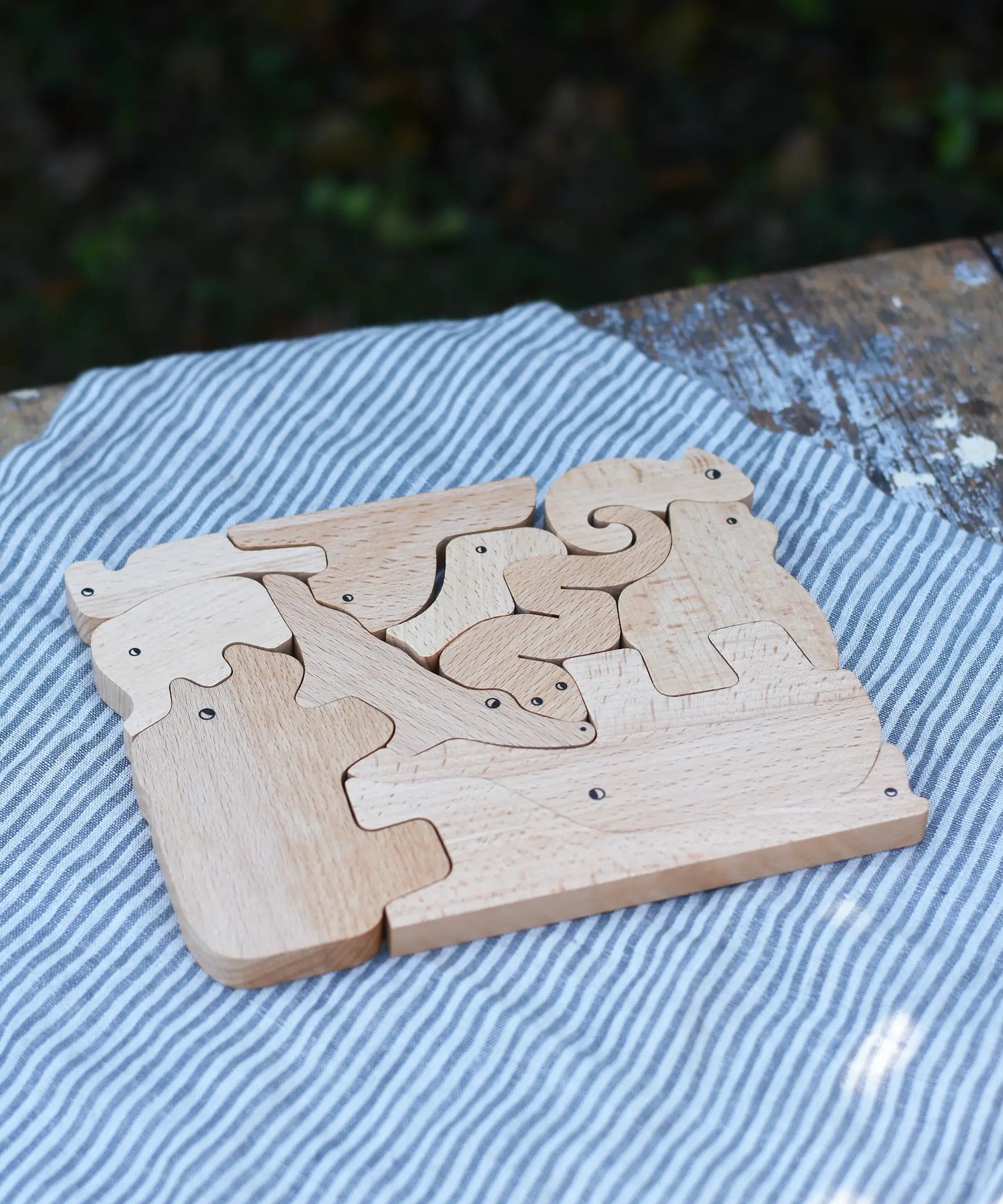 Bajo jungle puzzle shown on the natural wood side. Puzzle is made up of different animal shaped pieces.