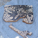 Bajo jungle puzzle with black pattern placed on a able with one of the animal shaped pieces taken out and placed besides it. 