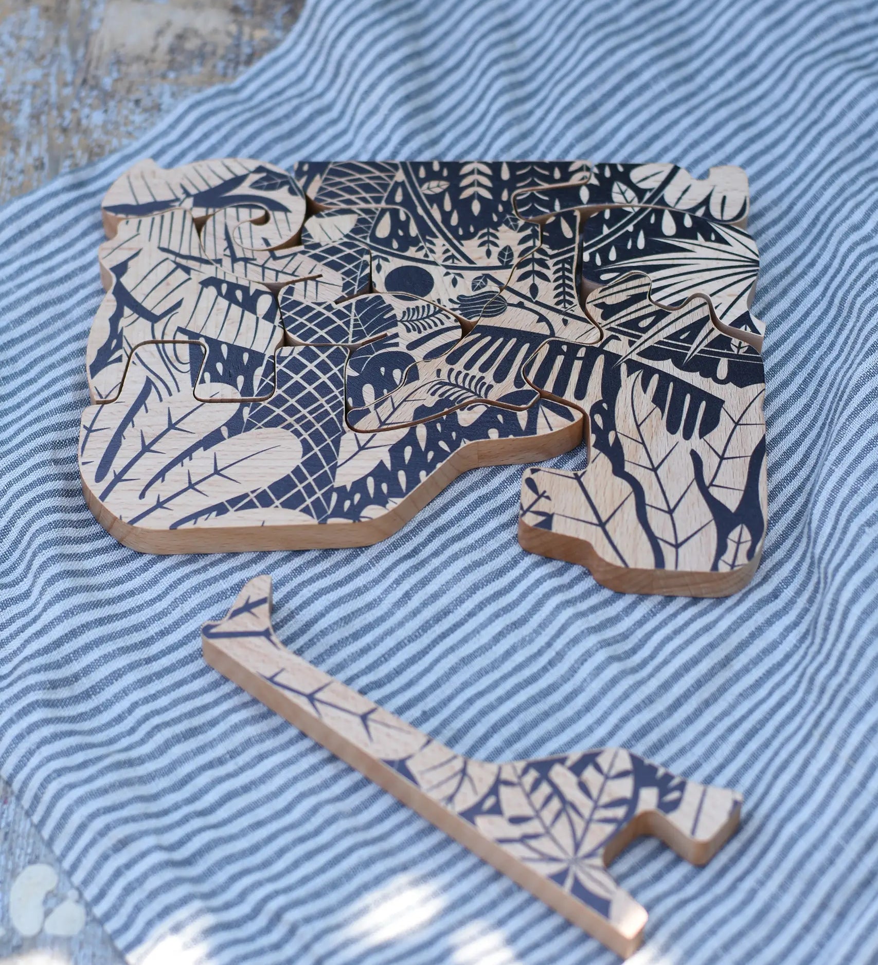 Bajo jungle puzzle with black pattern placed on a able with one of the animal shaped pieces taken out and placed besides it. 