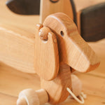 Close up of the handmade natural wooden pull along Bajo dachshund dog on a wooden floor