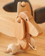 Close up of the handmade natural wooden pull along Bajo dachshund dog on a wooden floor