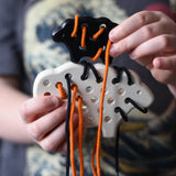 Bajo wooden lacing sheep and lamb toy with orange and black laces in a child'd hands.