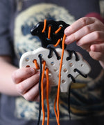 Bajo wooden lacing sheep and lamb toy with orange and black laces in a child'd hands.