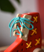 Close up of the blue laces tied up on the Bajo red lacing shoe.