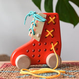 Bajo red lacing shoe wooden push along toy placed on a rattan stool in the Babipur playroom.