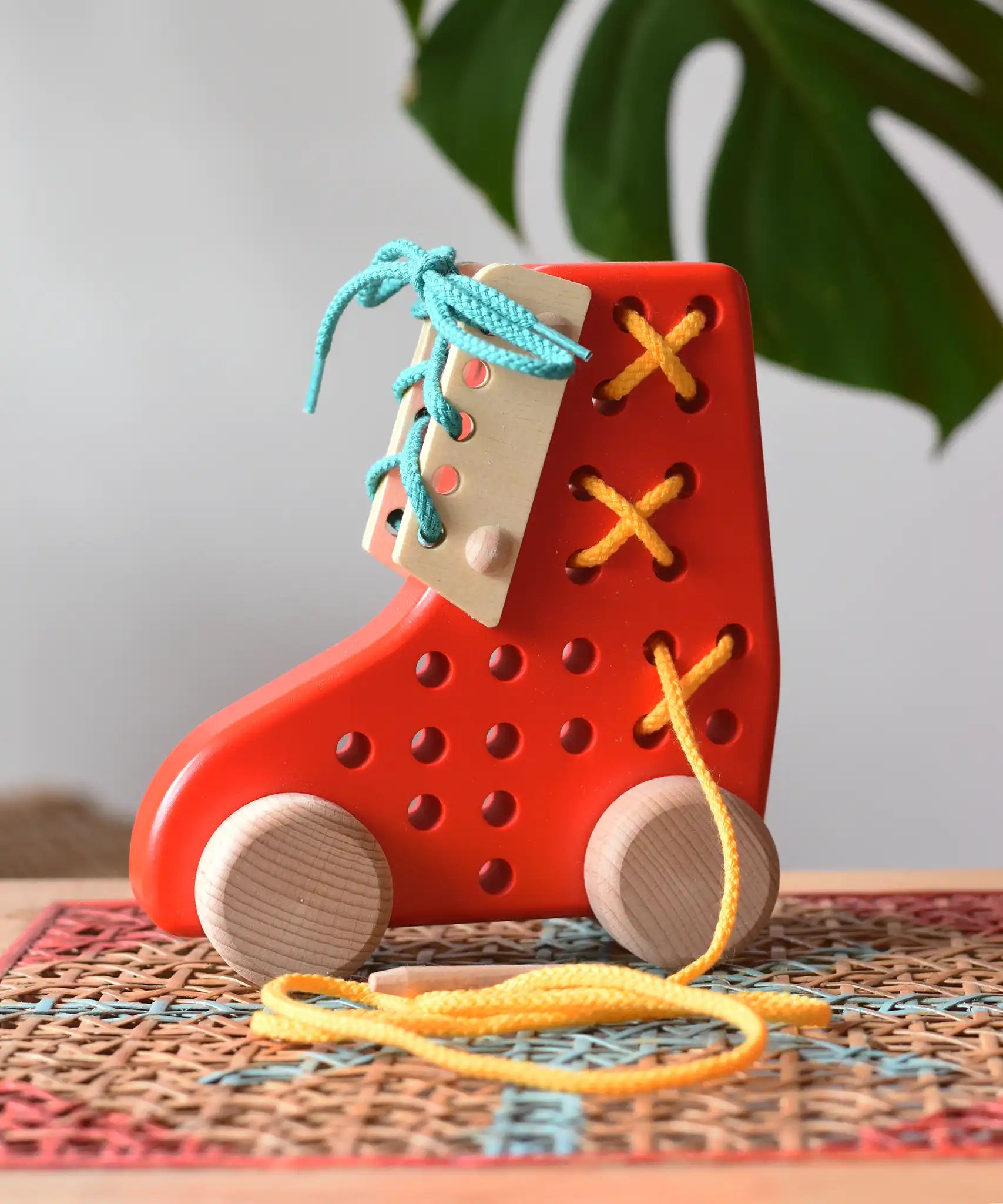 Bajo red lacing shoe wooden push along toy placed on a rattan stool in the Babipur playroom.