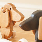 Close up of the Bajo natural wooden pull along dachshund toy dog next to the dark oak Bajo dachshund toy