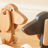 Close up of the Bajo natural wooden pull along dachshund toy dog next to the dark oak Bajo dachshund toy