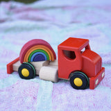 Grimm's mini rainbow placed on teh back of the cab of the Bajo large truck and trailer wooden toy.