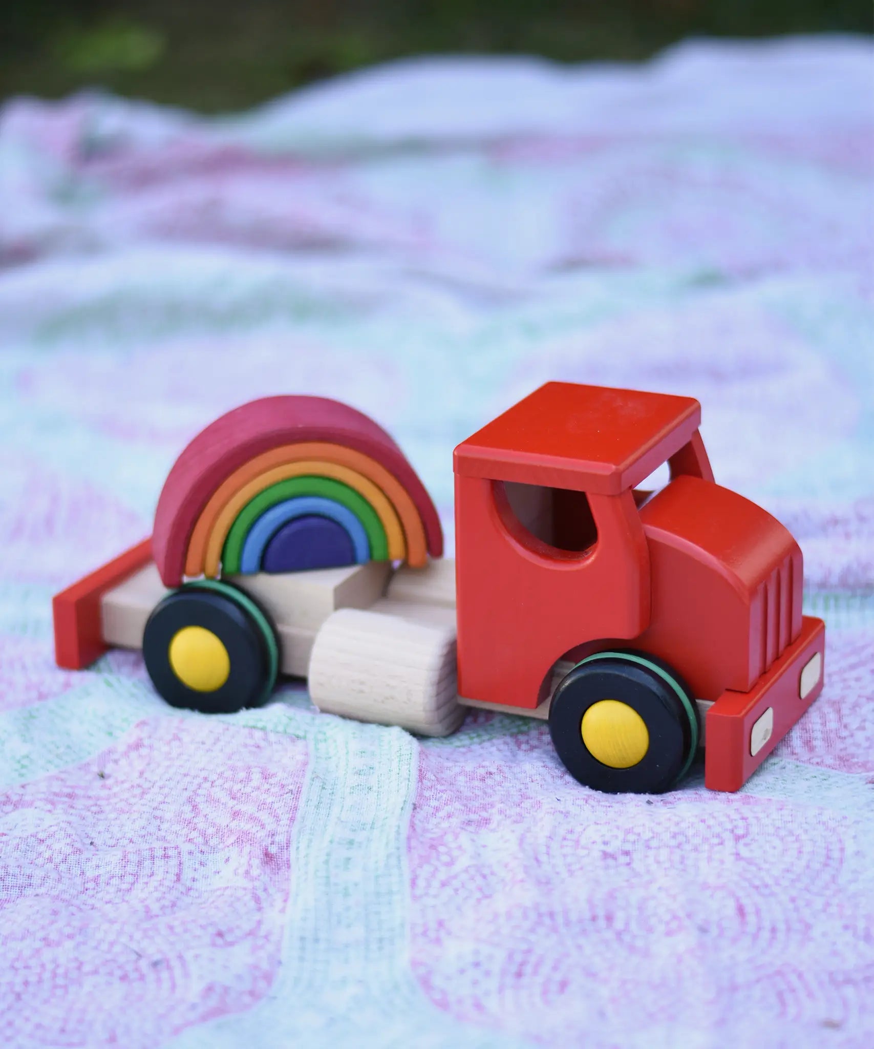 Grimm's mini rainbow placed on teh back of the cab of the Bajo large truck and trailer wooden toy.