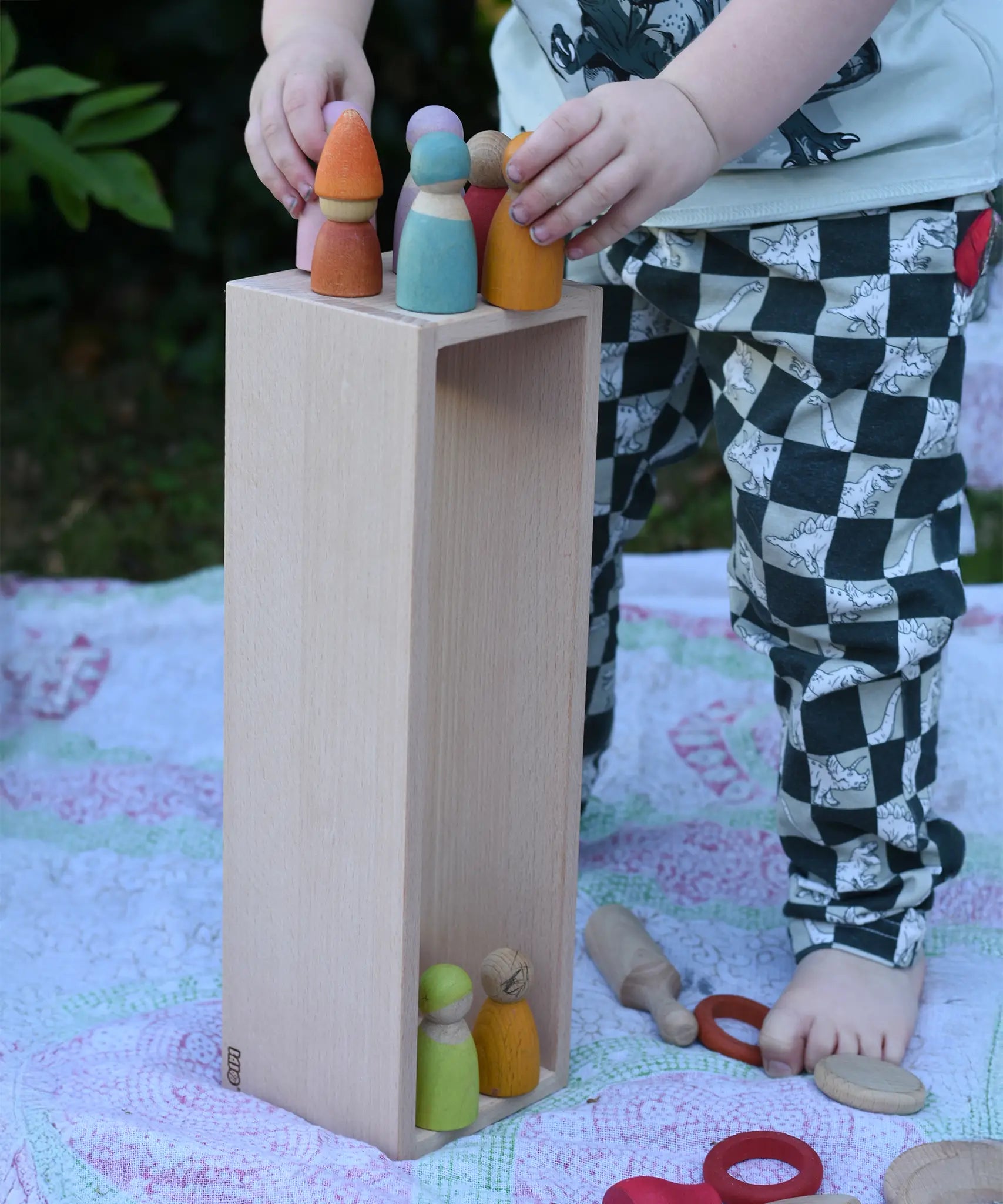The wooden box from the Bajo large truck and trailer wooden toy placed upright with wooden peg dolls placed inside and on top. 
