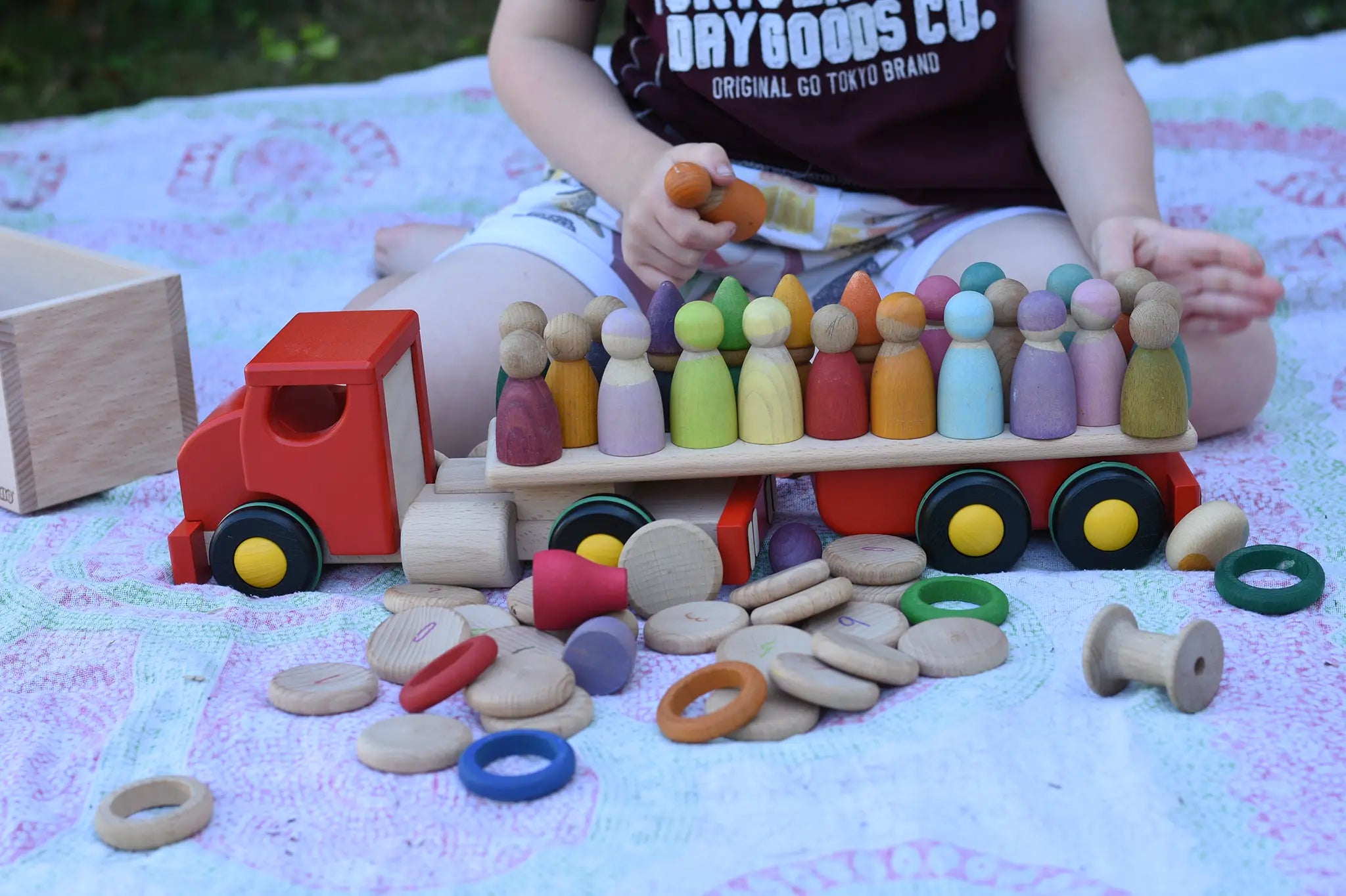 Bajo large truck and trailer wooden toy with lots of Grapat and Grimm's wooden peg dolls placed on the trailer.