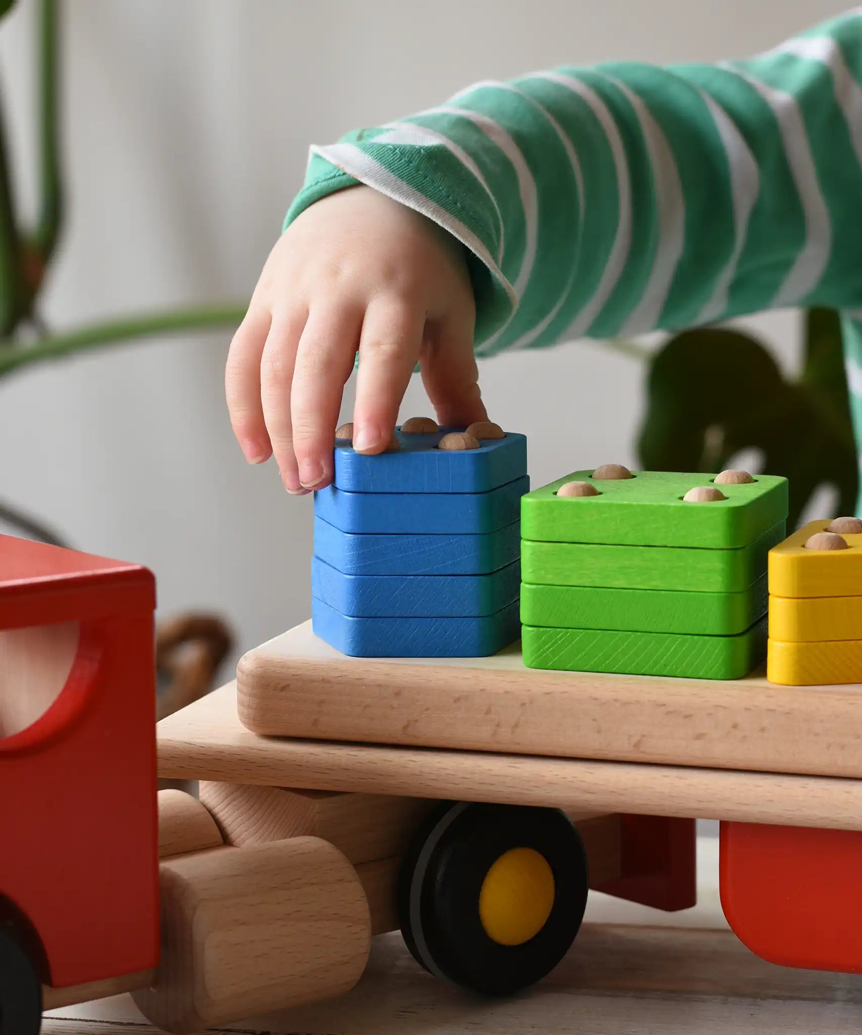 Close up of a child playing with the Bajo large red cargo truck and wooden shape sorter toy.