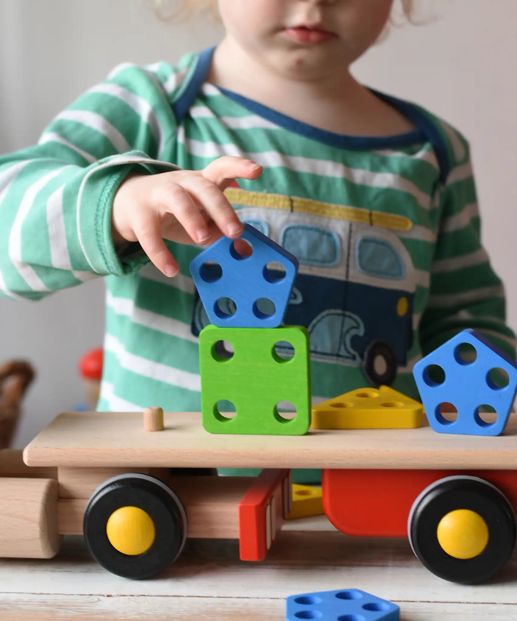 Child stacking shapes on the back of the Bajo large red cargo truck and wooden shape sorter toy.