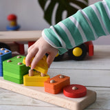 Close up of a child playing with the Bajo large red cargo truck and wooden shape sorter toy. The shape sorter base has been taken off the lorry.