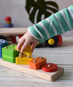 Close up of a child playing with the Bajo large red cargo truck and wooden shape sorter toy. The shape sorter base has been taken off the lorry.