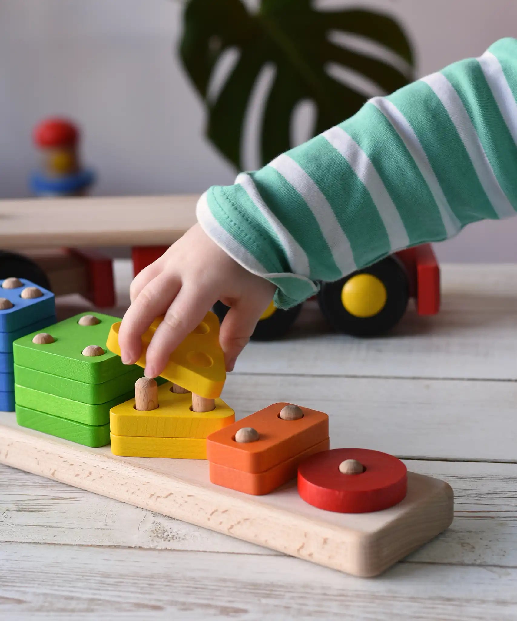 Close up of a child playing with the Bajo large red cargo truck and wooden shape sorter toy. The shape sorter base has been taken off the lorry.