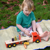 A child playing with the Bajo large red cargo truck and wooden shape sorter toy placing Grapat Wild Crew peg dolls on the back. 