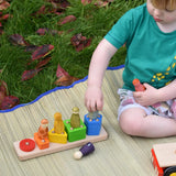 Child playing with the shape sorter from the Bajo large red cargo truck, placing Grapat wooden wild crew peg dolls on the corresponding colours. 