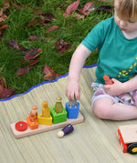 Child playing with the shape sorter from the Bajo large red cargo truck, placing Grapat wooden wild crew peg dolls on the corresponding colours. 