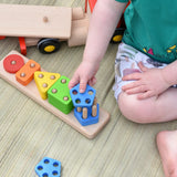 Close up of child placing a wooden shape on the Bajo large red cargo truck and wooden shape sorter toy base.
