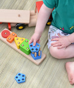 Close up of child placing a wooden shape on the Bajo large red cargo truck and wooden shape sorter toy base.