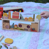 Grapat Happy Place loose parts placed on the wooden trailer from the  Bajo large truck and trailer wooden toy which has been placed on it's side and used as a frame.
