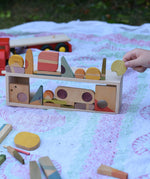 Grapat Happy Place loose parts placed on the wooden trailer from the  Bajo large truck and trailer wooden toy which has been placed on it's side and used as a frame.
