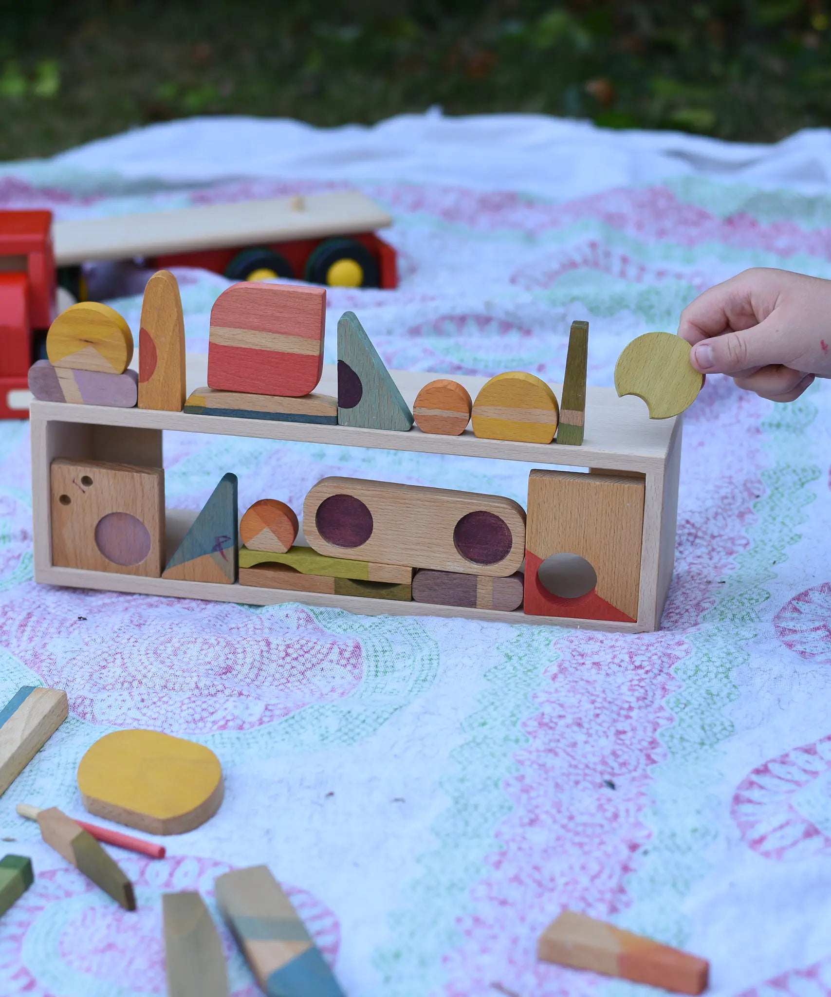 Grapat Happy Place loose parts placed on the wooden trailer from the  Bajo large truck and trailer wooden toy which has been placed on it's side and used as a frame.