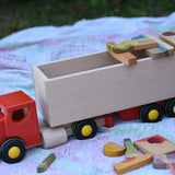 Bajo large truck and trailer wooden toy with loose parts from the Grapat Happy place set balanced on the trailer. 
