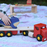 Child placing a Holztiger whale on the back of the Bajo large truck and trailer wooden toy with the trailer box removed. 