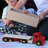 Child placing the trailer box onto the back of the Bajo large truck and trailer wooden toy.