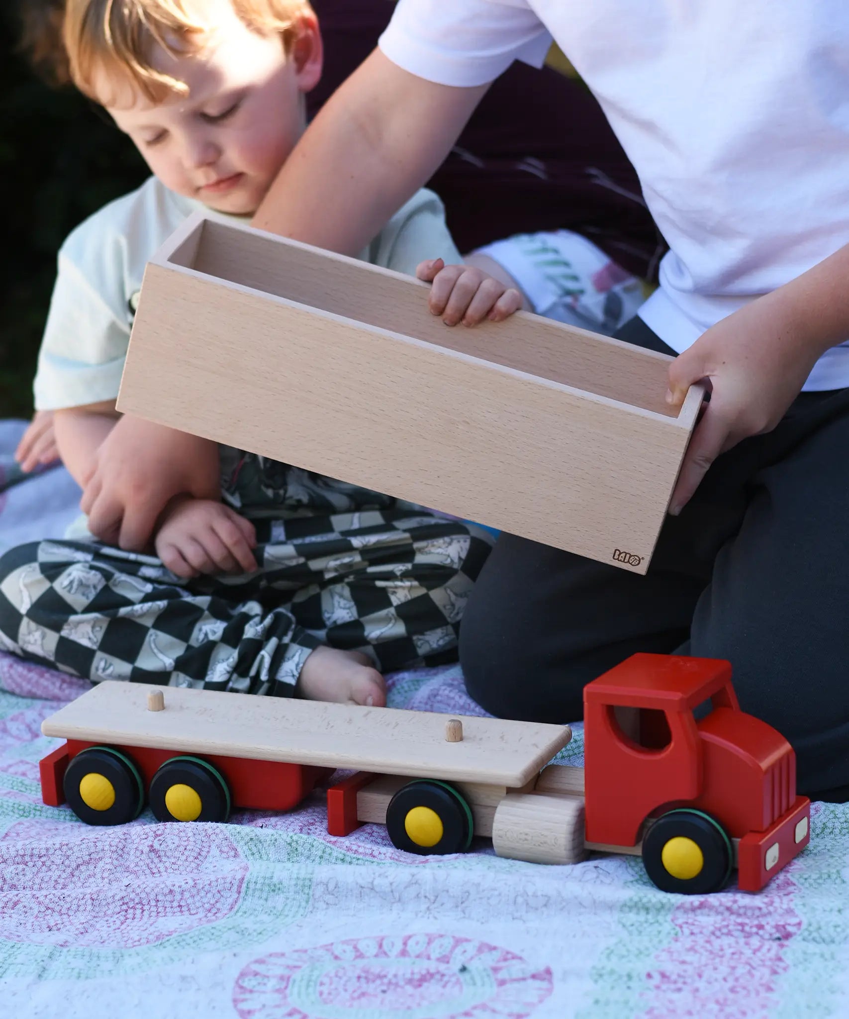 Child placing the trailer box onto the back of the Bajo large truck and trailer wooden toy.